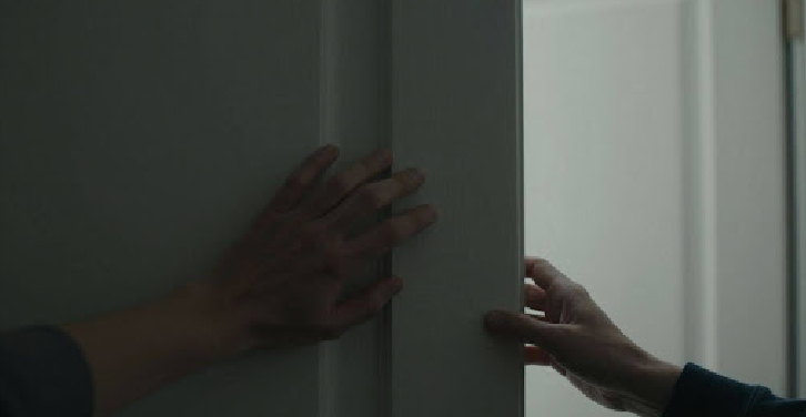 Domestic violence victim's hand reaching out from behind a door.